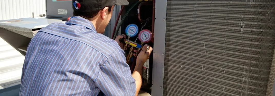 HVAC technician servicing a condenser unit in Conewago